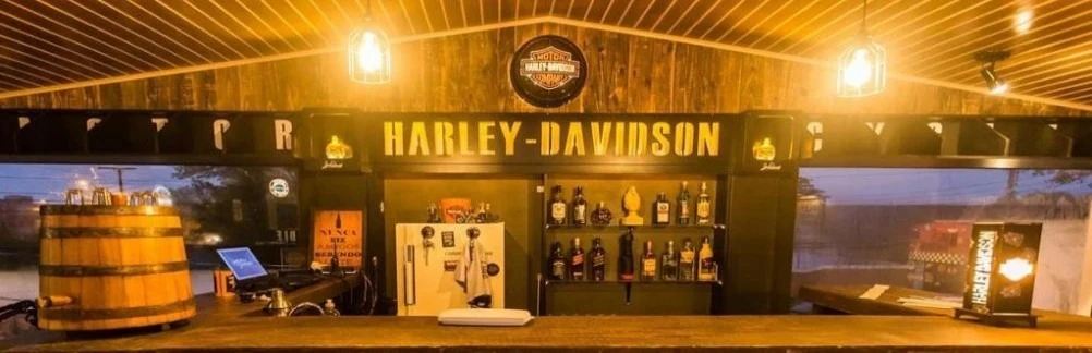 Balcão do Riders Bar com letreiro Harley-Davidson e barril